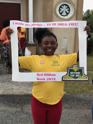 A girl poses with a sign saying "I made the pledge to be drug free! Red Ribbon Week 2019."