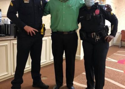 Two police officers with a man in a green shirt. All three are wearing masks.
