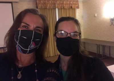 Two women wearing masks in a banquet hall.