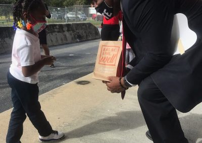 The mayor handing a goodie bag to a young kid.
