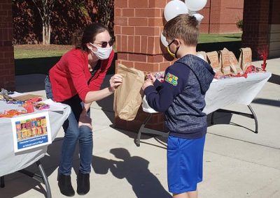 A woman handing a goodie bag to a young boy.