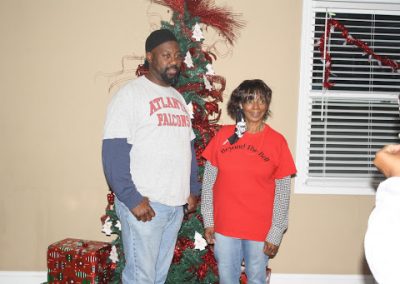 A man and a woman stand in front of a Christmas tree