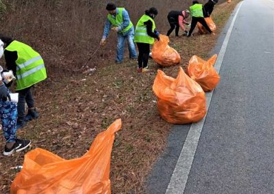 Six people cleaning up garbage along the roadside