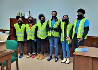 Six young adults wearing yellow vests