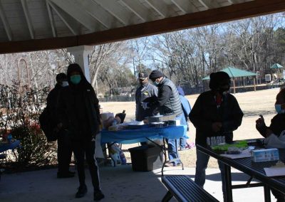 Groups of people standing around tables with food and running supplies.